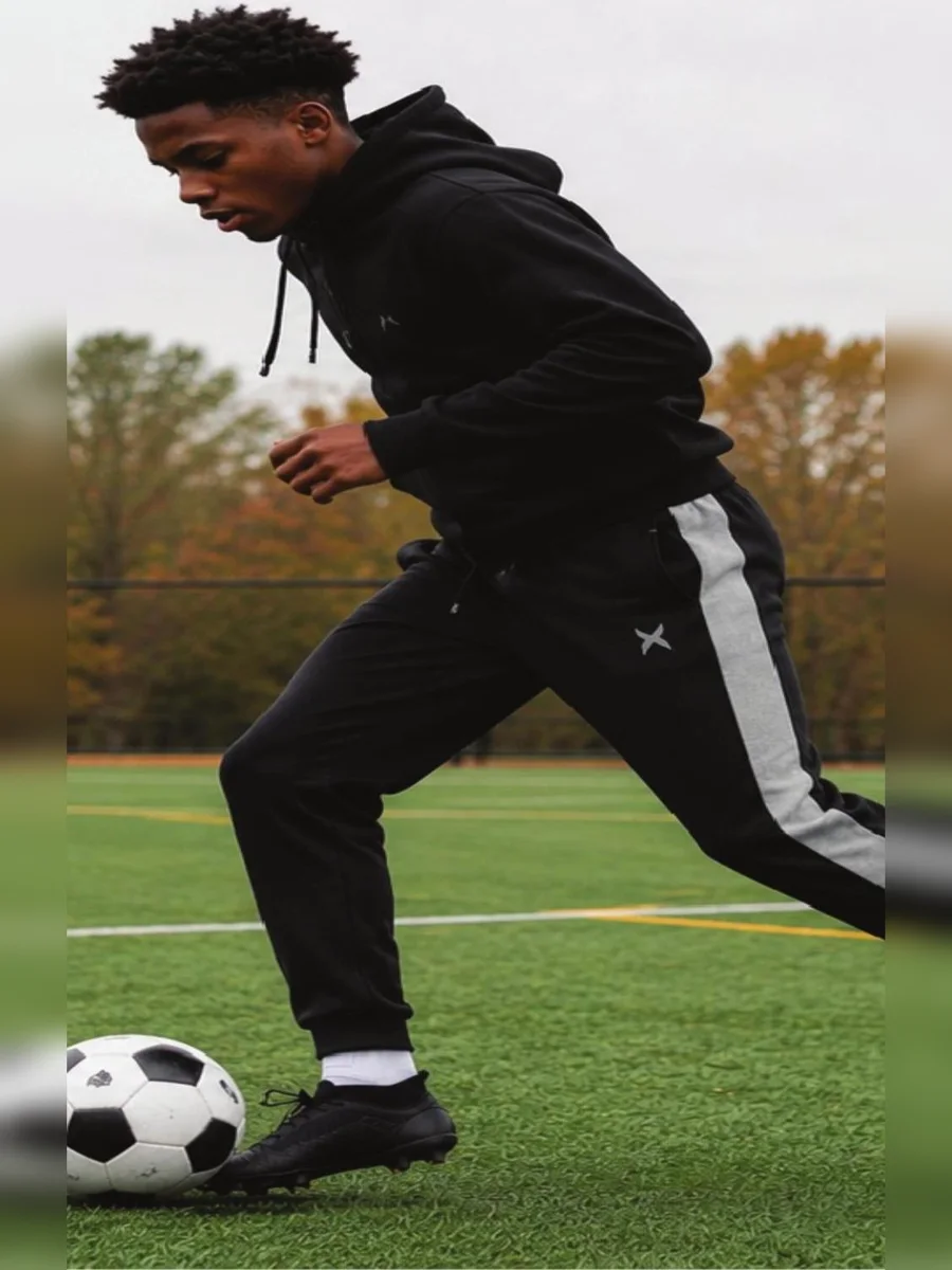 Boy running on a field in Game Time fleece hoodie and jogger